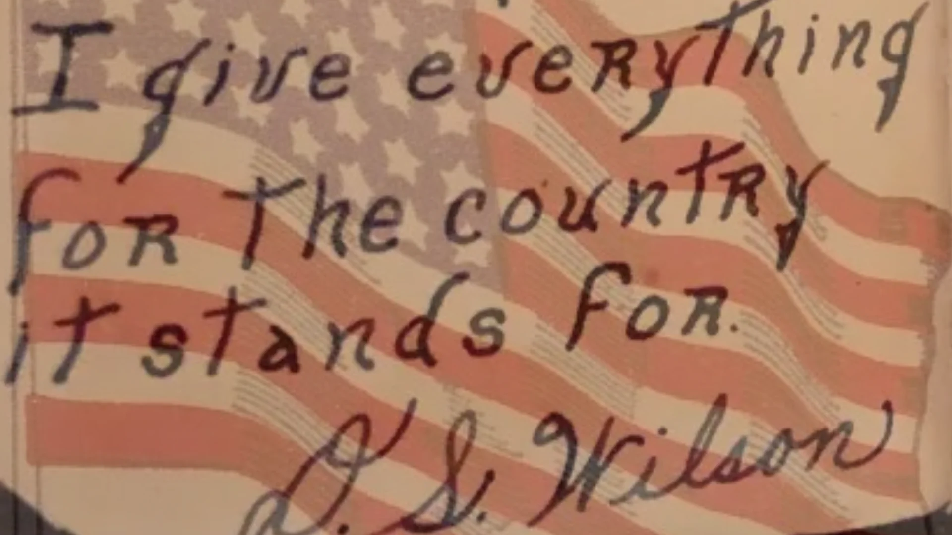 Handwritten patriotic message over a waving red, white, and blue American flag background, conveying devotion to the country.