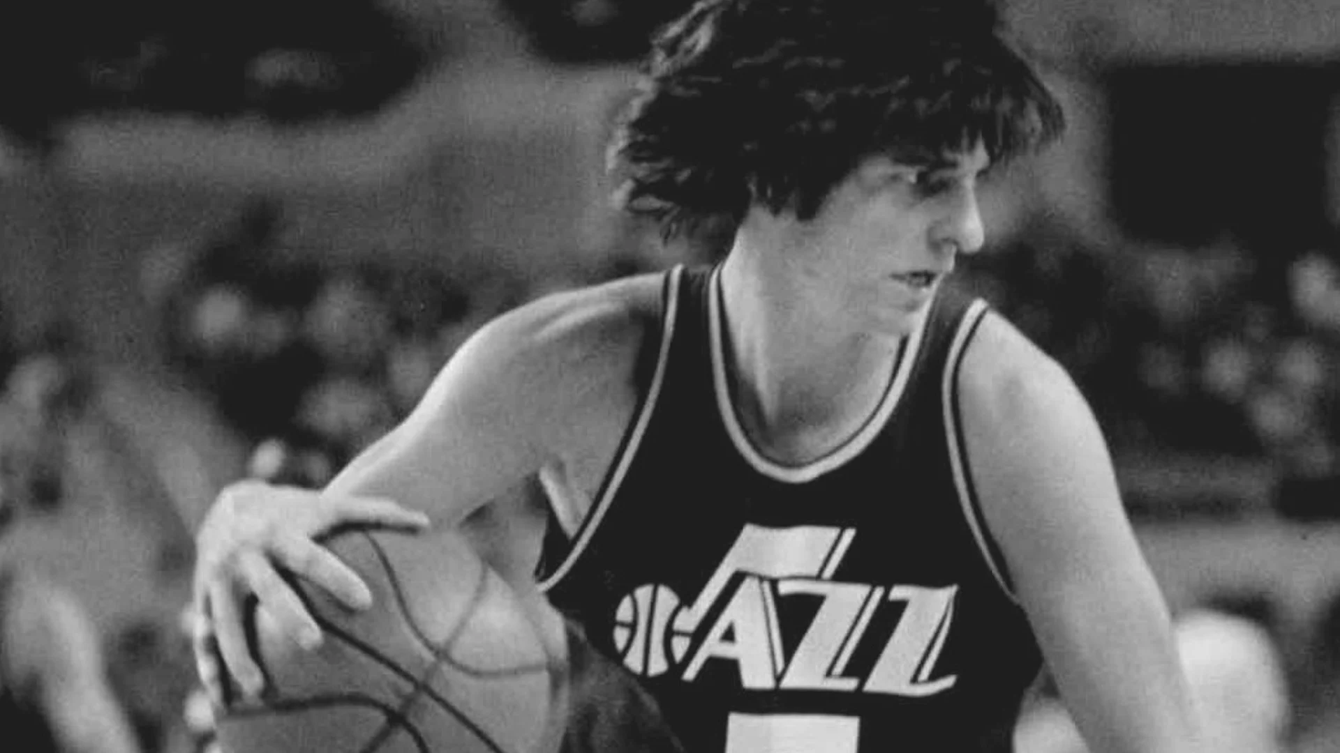 Black-and-white basketball player in a Utah Jazz jersey dribbling during a game.